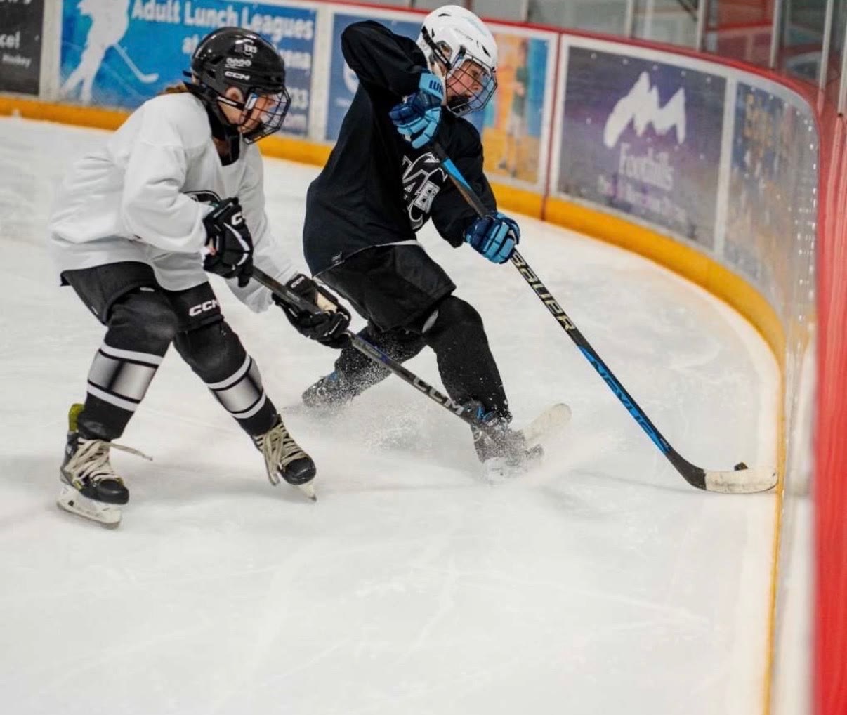 Driving into the corner with a defender sealed off on her outside hip, body between the opponent and the puck
