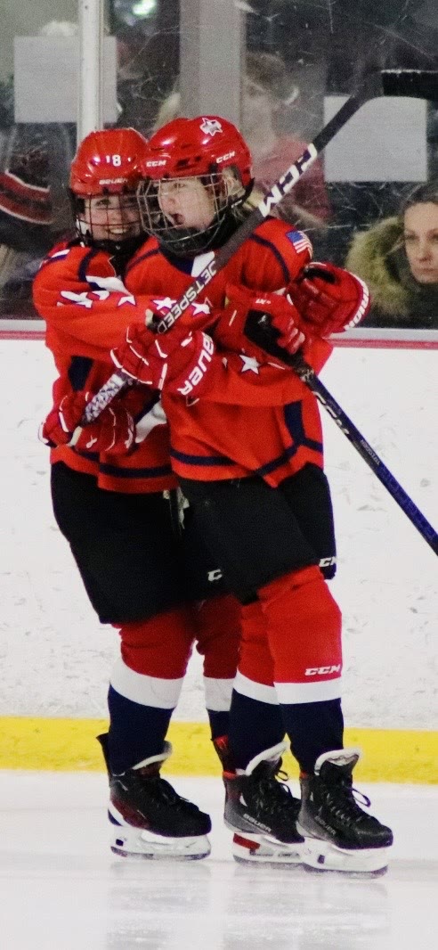 Grinning with her arms around a teammate after a goal